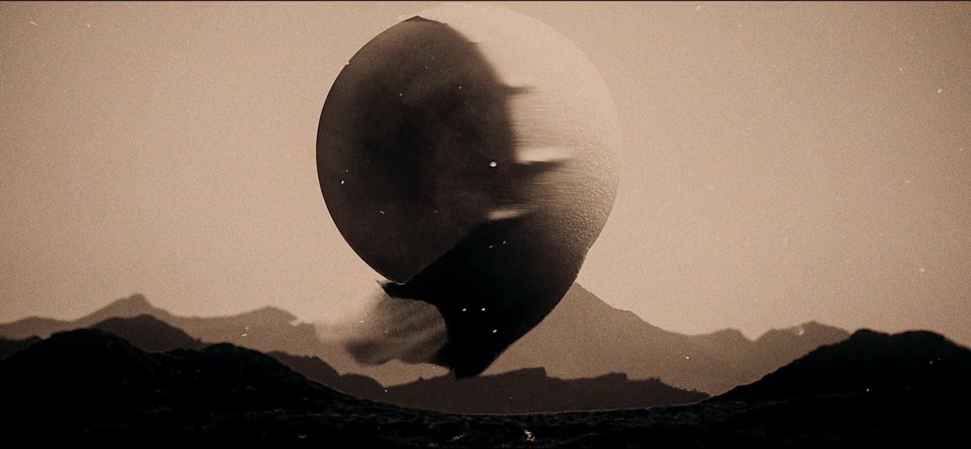 Textured abstract orb suspended above a sepia mountain landscape.